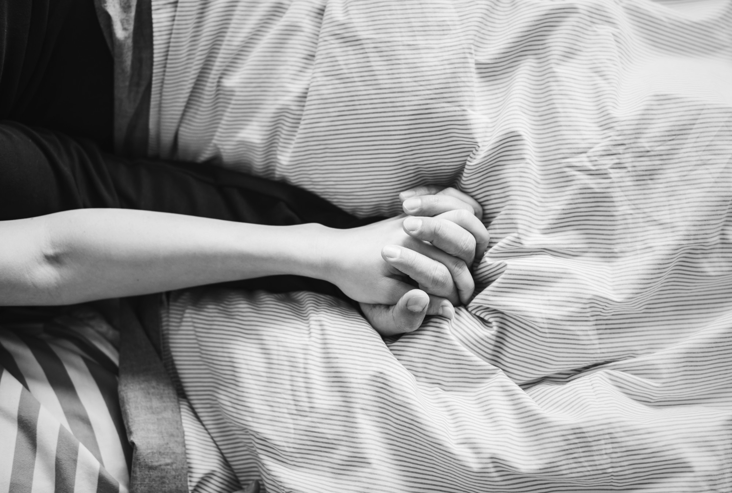 couple holding hands in bed